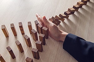 a business woman stopping falling dominos representing risk management