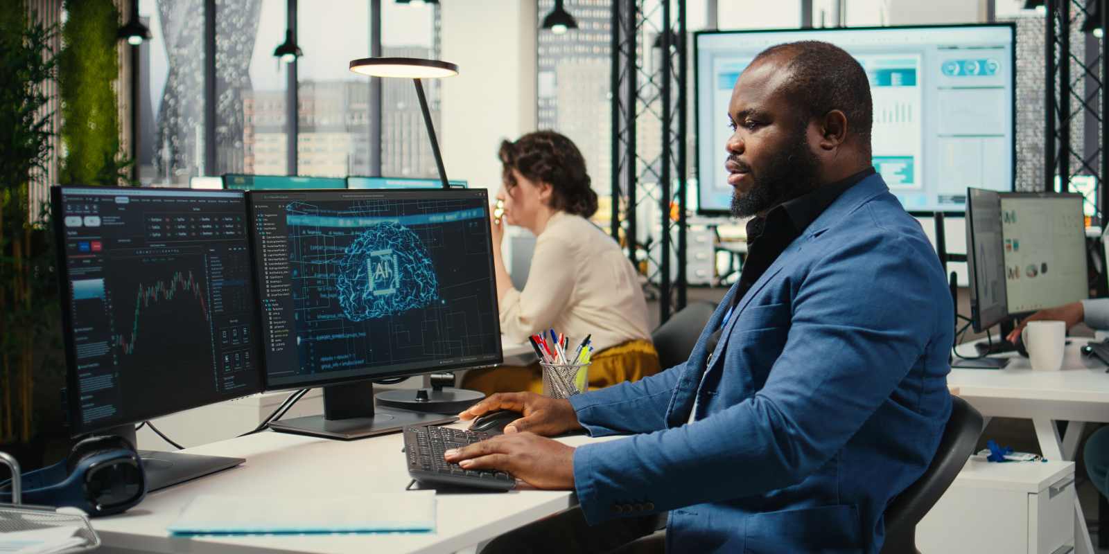 An IT professional working on dual monitors displaying AI and data analytics in a modern office representing skilled IT staff augmentation