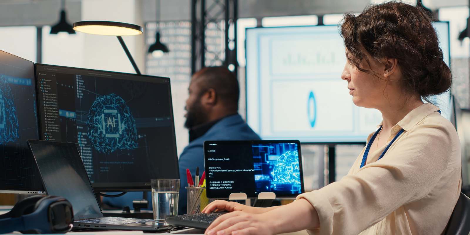  IT professionals working on AI and coding tasks across multiple screens representing cybersecurity IT staff augmentation