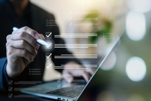business professional using a laptop with digital checklist and check marks