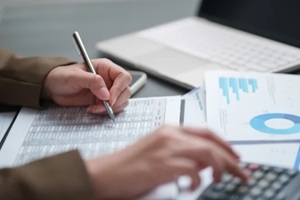 businesswoman calculating and reviewing financial reports with charts and data at an office desk